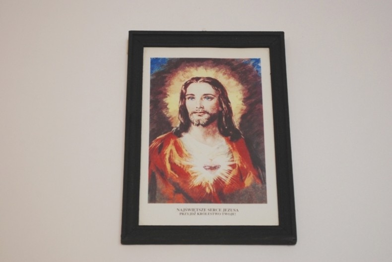 Obrazek wiszący na ścianie przedstawia Jezusa z sercem płonącym miłością.