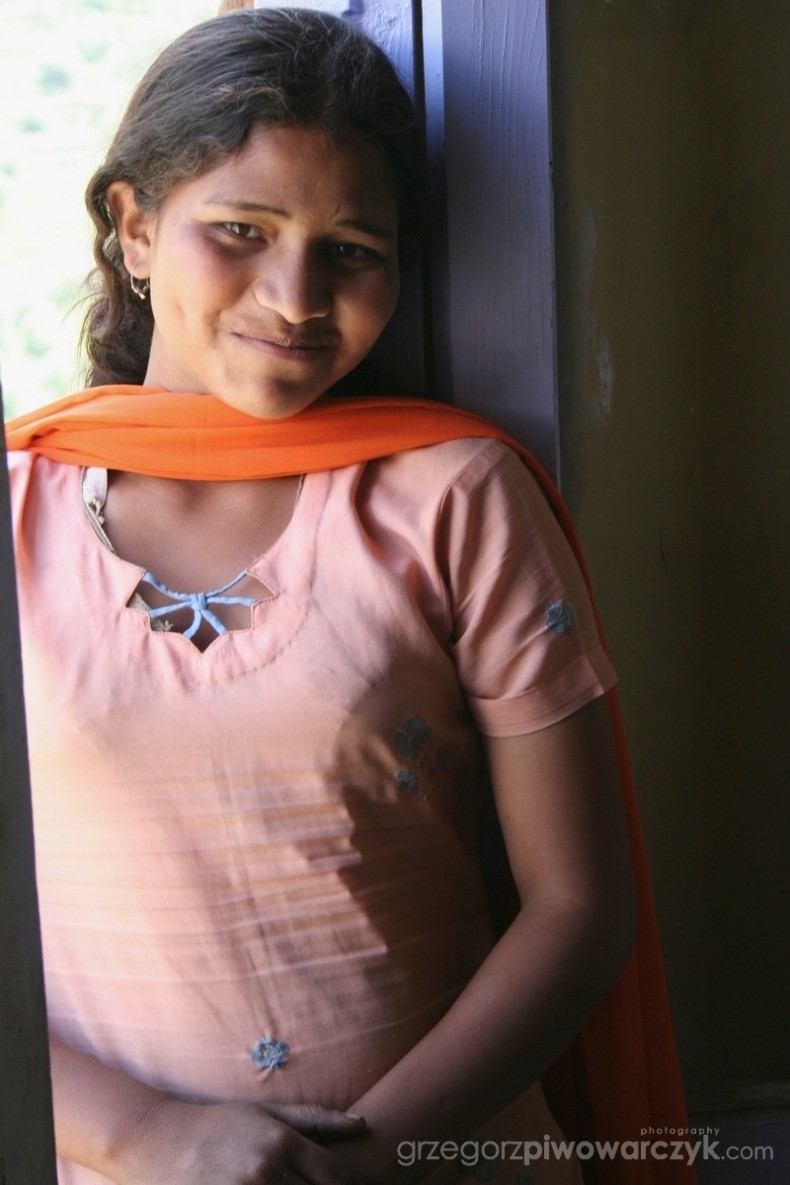 Piękna młoda kobieta, stojąc przy oknie uśmiecha się. Indie, Himachal Pradesh, Keylong. Beautiful indian woman, portrait.